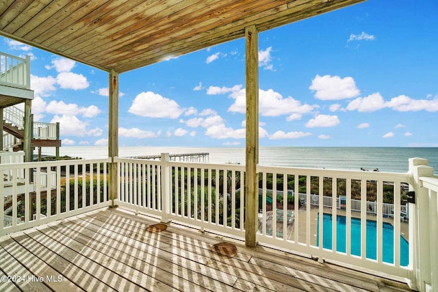 wooden deck with a water view, a patio, and a view of the beach