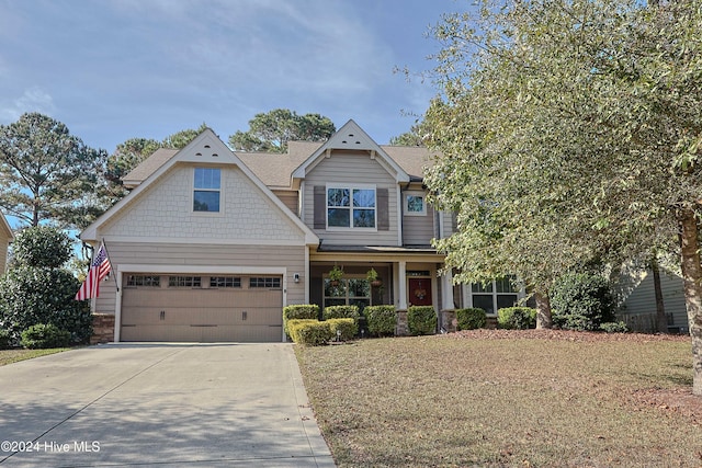 craftsman inspired home featuring a garage and a front lawn