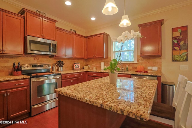 kitchen featuring ornamental molding, stainless steel appliances, hanging light fixtures, a breakfast bar area, and a center island