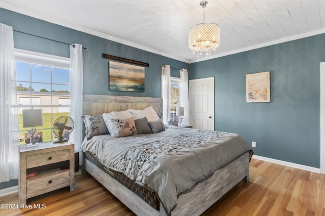 bedroom with wood-type flooring, a chandelier, and crown molding