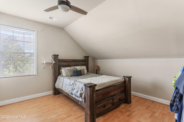 bedroom with light hardwood / wood-style floors, ceiling fan, multiple windows, and lofted ceiling