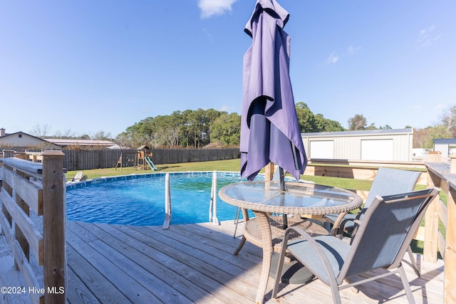 view of pool featuring a playground, a yard, and a deck