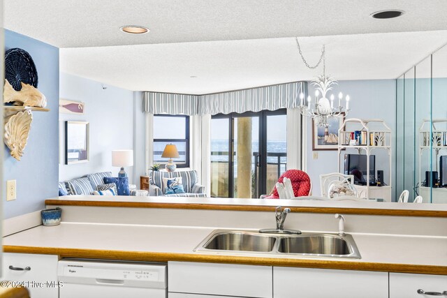 kitchen featuring a sink, white cabinetry, light countertops, dishwasher, and an inviting chandelier