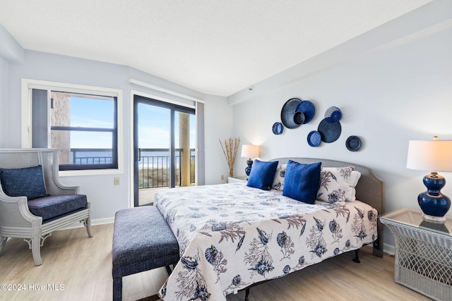 bedroom featuring access to exterior, baseboards, and wood finished floors