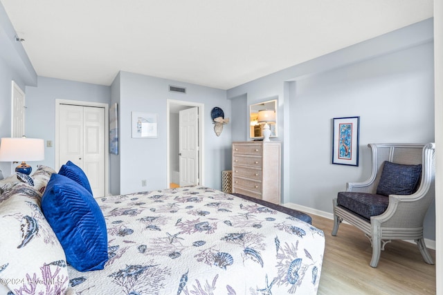 bedroom featuring a closet, light wood-type flooring, visible vents, and baseboards