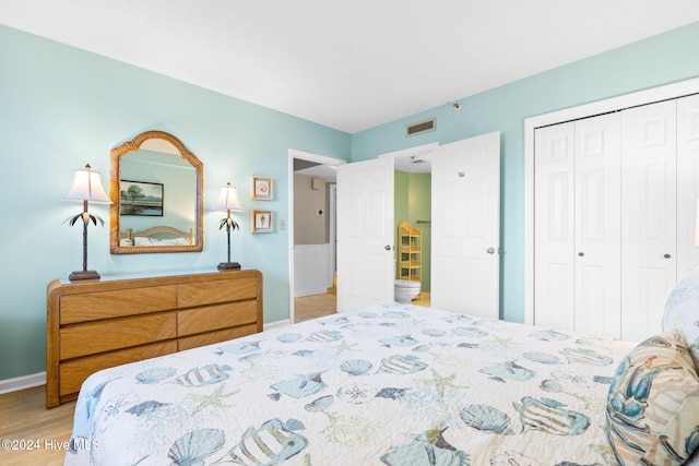 bedroom with a closet, wood finished floors, visible vents, and baseboards