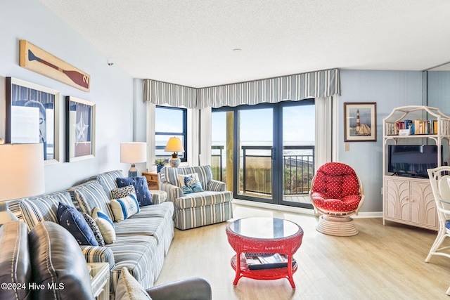 living room with a textured ceiling, baseboards, and wood finished floors