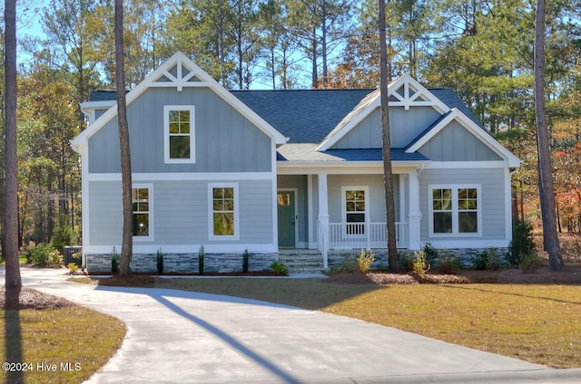 craftsman inspired home with a front lawn, a porch, board and batten siding, and roof with shingles