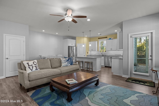 living room with ceiling fan, plenty of natural light, dark wood-type flooring, and sink