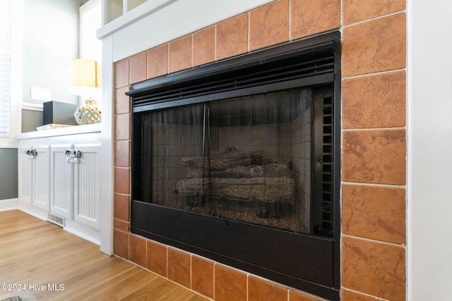 room details with a tile fireplace, visible vents, and wood finished floors