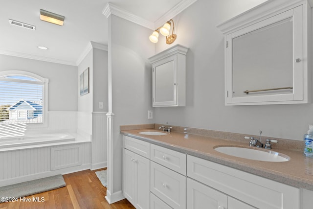 bathroom with hardwood / wood-style floors, a tub to relax in, vanity, and ornamental molding