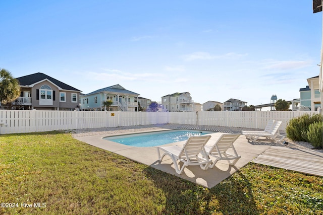 view of swimming pool featuring a yard, a patio area, and a residential view