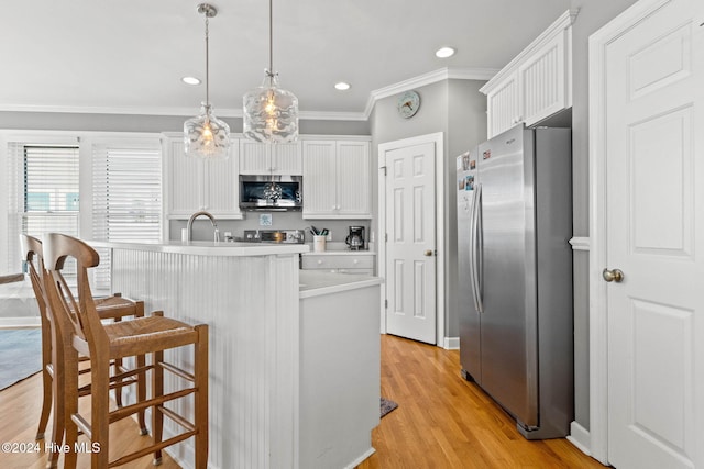 kitchen featuring stainless steel appliances, white cabinets, ornamental molding, light hardwood / wood-style flooring, and decorative light fixtures