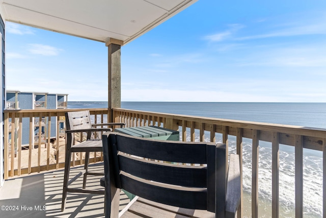 wooden terrace featuring a beach view and a water view