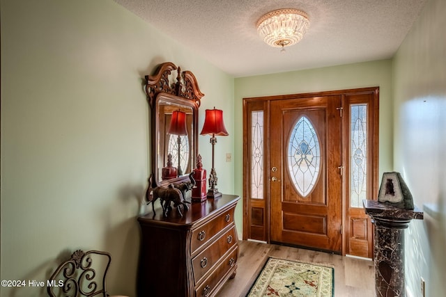 foyer entrance with light wood-type flooring and a textured ceiling