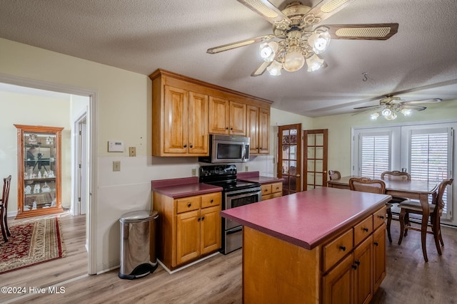 kitchen with black range with electric stovetop, light hardwood / wood-style flooring, a kitchen island, and a textured ceiling