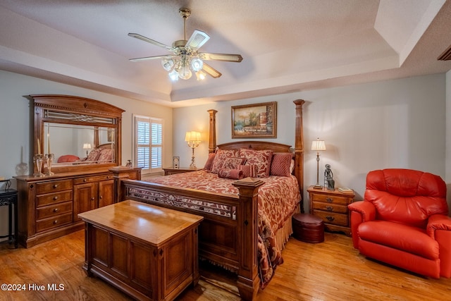 bedroom featuring a tray ceiling, ceiling fan, and light hardwood / wood-style floors