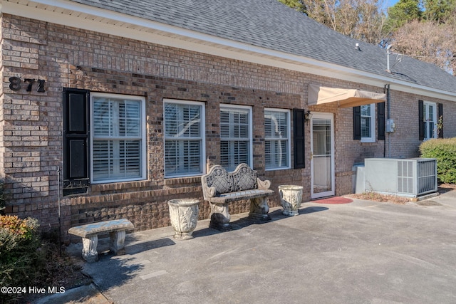 back of property with central AC unit and a patio