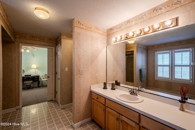 bathroom with ceiling fan, vanity, and a textured ceiling