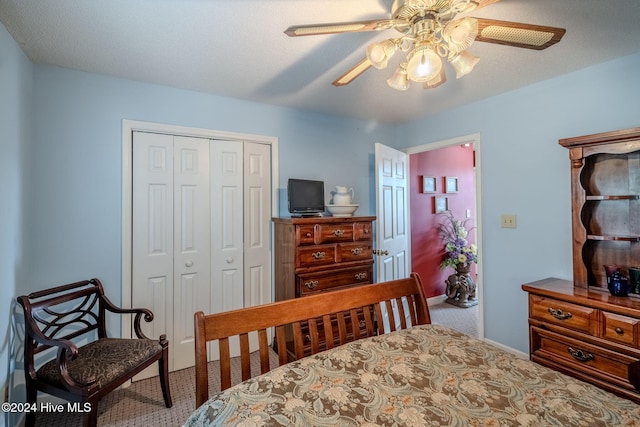 carpeted bedroom with ceiling fan, a closet, and a textured ceiling