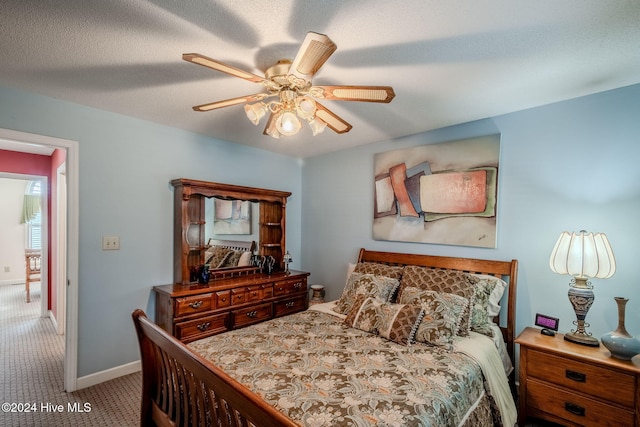 bedroom with a textured ceiling, light colored carpet, and ceiling fan