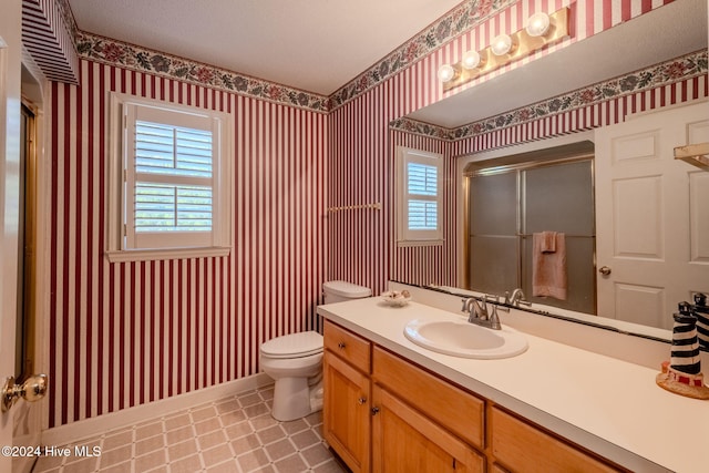 bathroom featuring vanity, a healthy amount of sunlight, a shower with shower door, and toilet