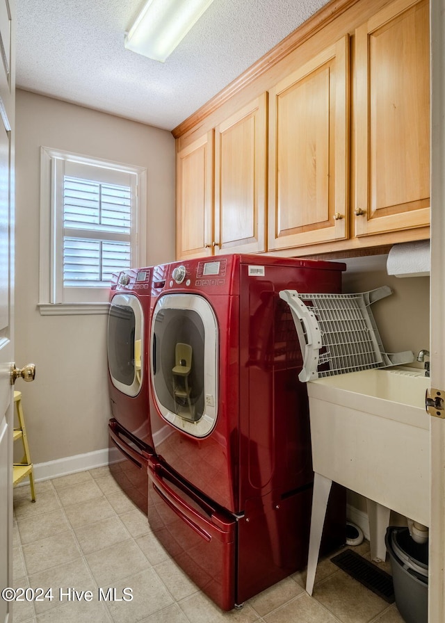 washroom with cabinets, washer and dryer, and a textured ceiling