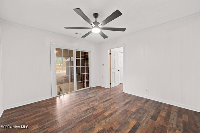 spare room featuring ceiling fan, ornamental molding, dark wood-type flooring, and wooden walls