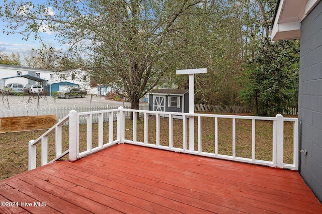 wooden terrace featuring a yard and a shed