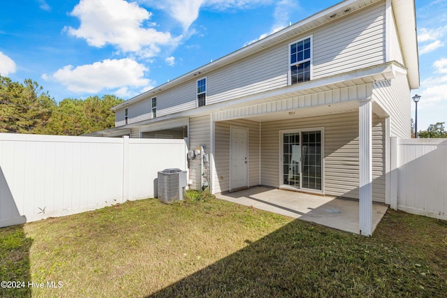 rear view of property with a patio area, a yard, and central AC