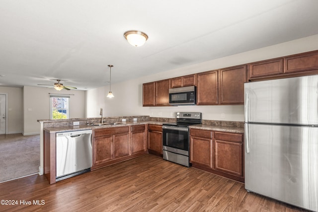 kitchen with hanging light fixtures, dark wood-type flooring, sink, and stainless steel appliances