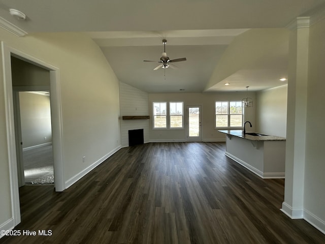 unfurnished living room featuring a ceiling fan, a fireplace, baseboards, and dark wood-type flooring