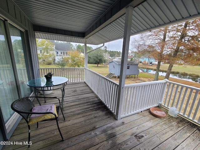 deck with a water view and a shed