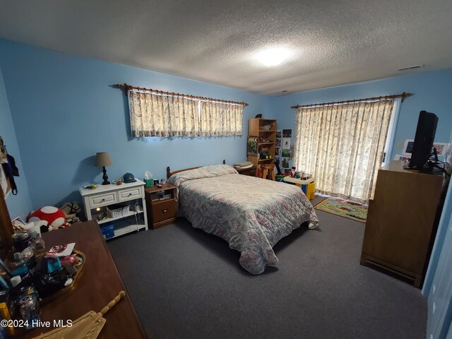 bedroom featuring carpet, a textured ceiling, and multiple windows