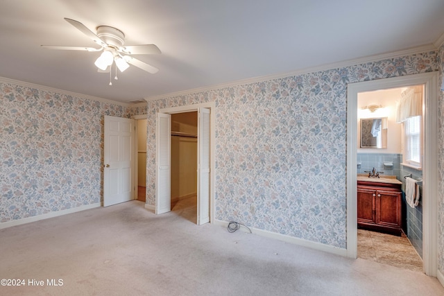 bedroom featuring ceiling fan, ensuite bathroom, light carpet, and sink