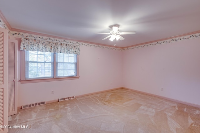 unfurnished room with ceiling fan, light colored carpet, and ornamental molding