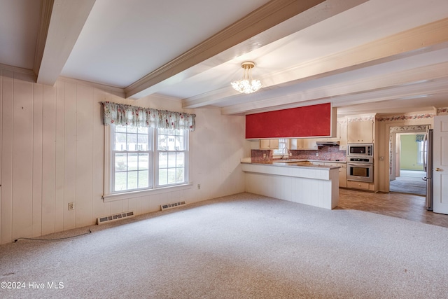 kitchen featuring kitchen peninsula, stainless steel appliances, sink, beamed ceiling, and a chandelier