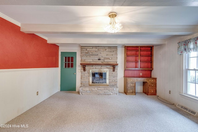 unfurnished living room with a stone fireplace, carpet flooring, ornamental molding, beam ceiling, and a chandelier