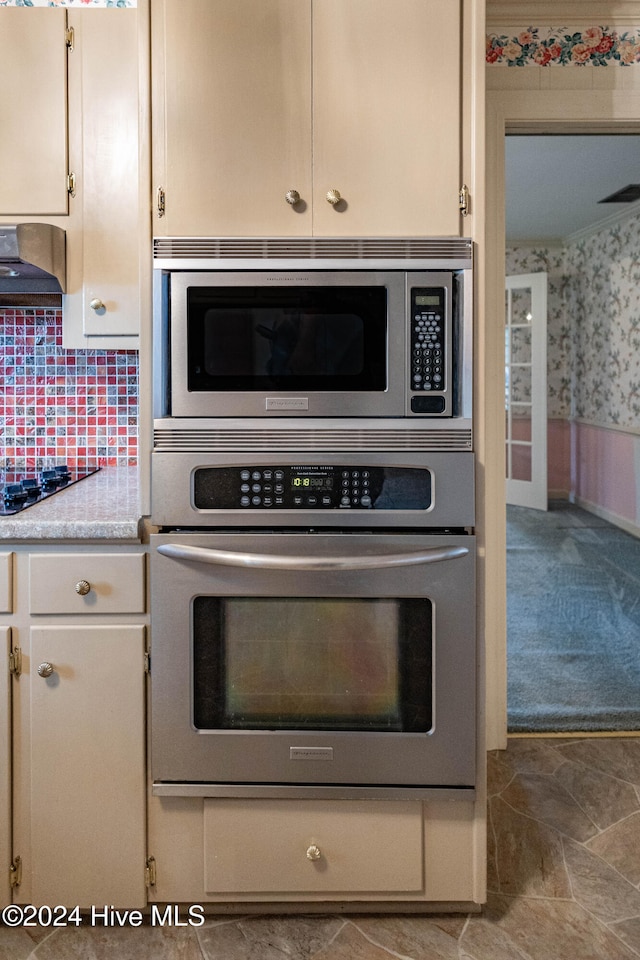 kitchen featuring white cabinets, appliances with stainless steel finishes, light colored carpet, and range hood