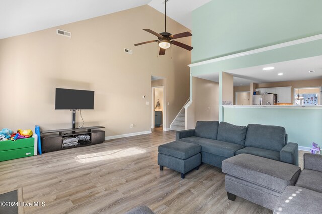 living room with light hardwood / wood-style floors, high vaulted ceiling, and ceiling fan