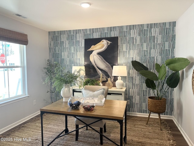 office space featuring an accent wall, wood finished floors, visible vents, and baseboards