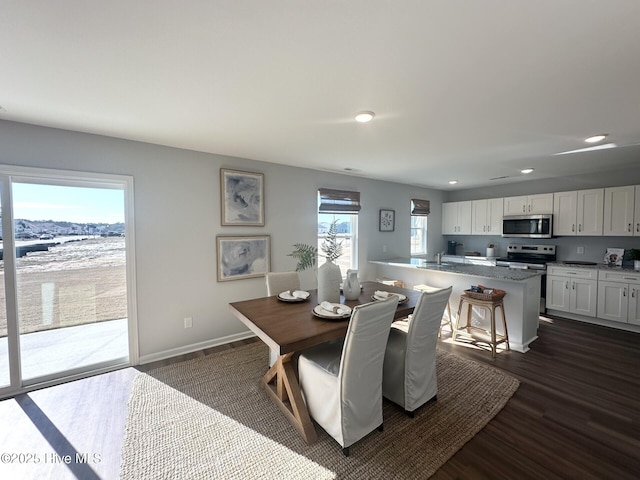 dining area featuring baseboards, dark wood finished floors, and recessed lighting