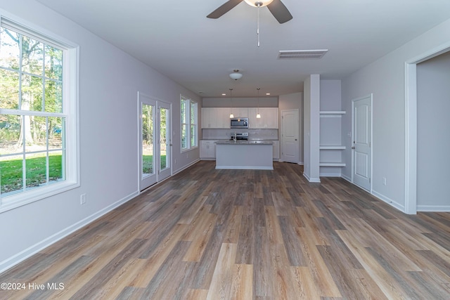 unfurnished living room featuring ceiling fan, dark hardwood / wood-style floors, and a wealth of natural light