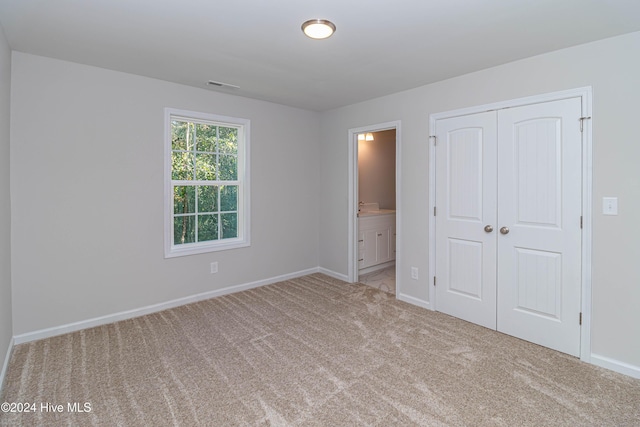 unfurnished bedroom with carpet, connected bathroom, and a closet