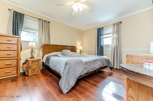 bedroom featuring ceiling fan, crown molding, and dark wood-type flooring