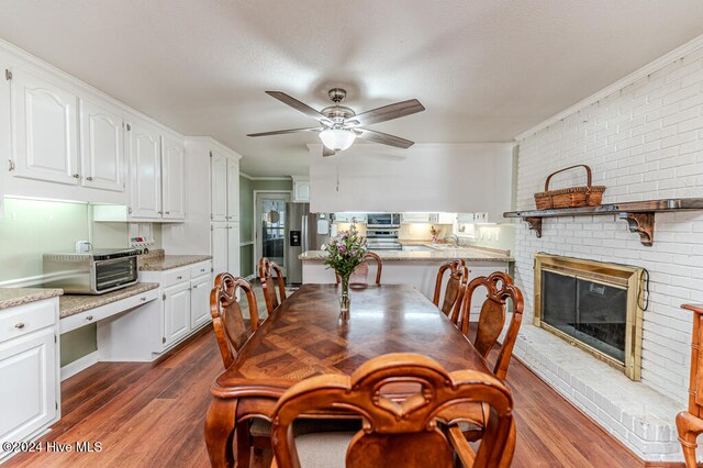 dining area with a fireplace, ornamental molding, dark wood-type flooring, and brick wall