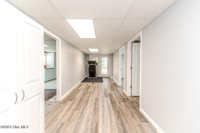 corridor featuring a paneled ceiling and light wood-type flooring