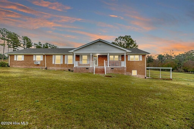 ranch-style house featuring covered porch and a yard