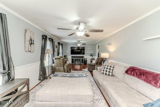 living room with hardwood / wood-style flooring, ceiling fan, and crown molding