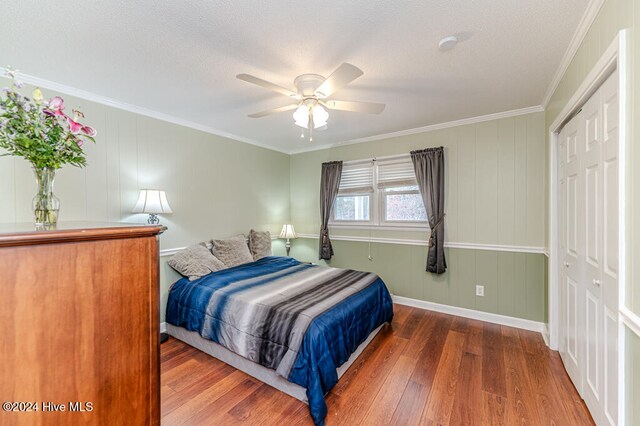 bedroom with a closet, dark hardwood / wood-style floors, ceiling fan, and crown molding